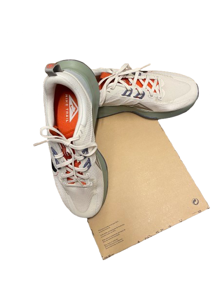 A pair of white athletic sneakers with orange and blue accents, displayed on a brown cardboard box against a white background.